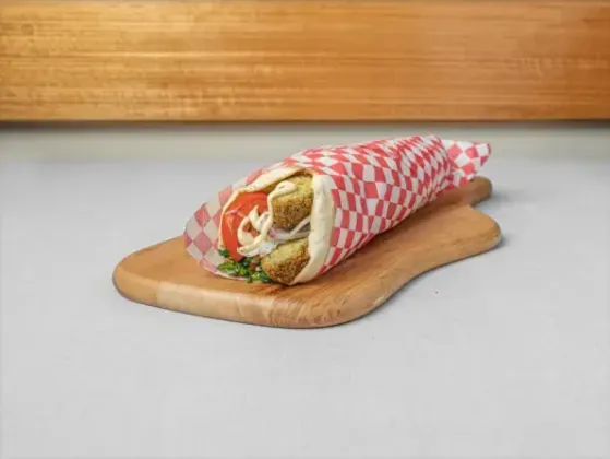Falafel wrap in red-check paper on a wooden board